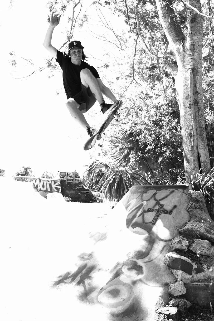 Duane Pitre grabbing his board mid-air during a tailgrab at a DIY skatepark