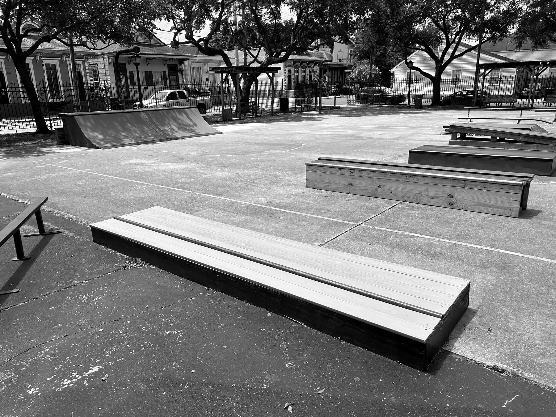 Empty skatepark with ramps, rails, and boxes on a sunny day in a New Orleans neighborhood
